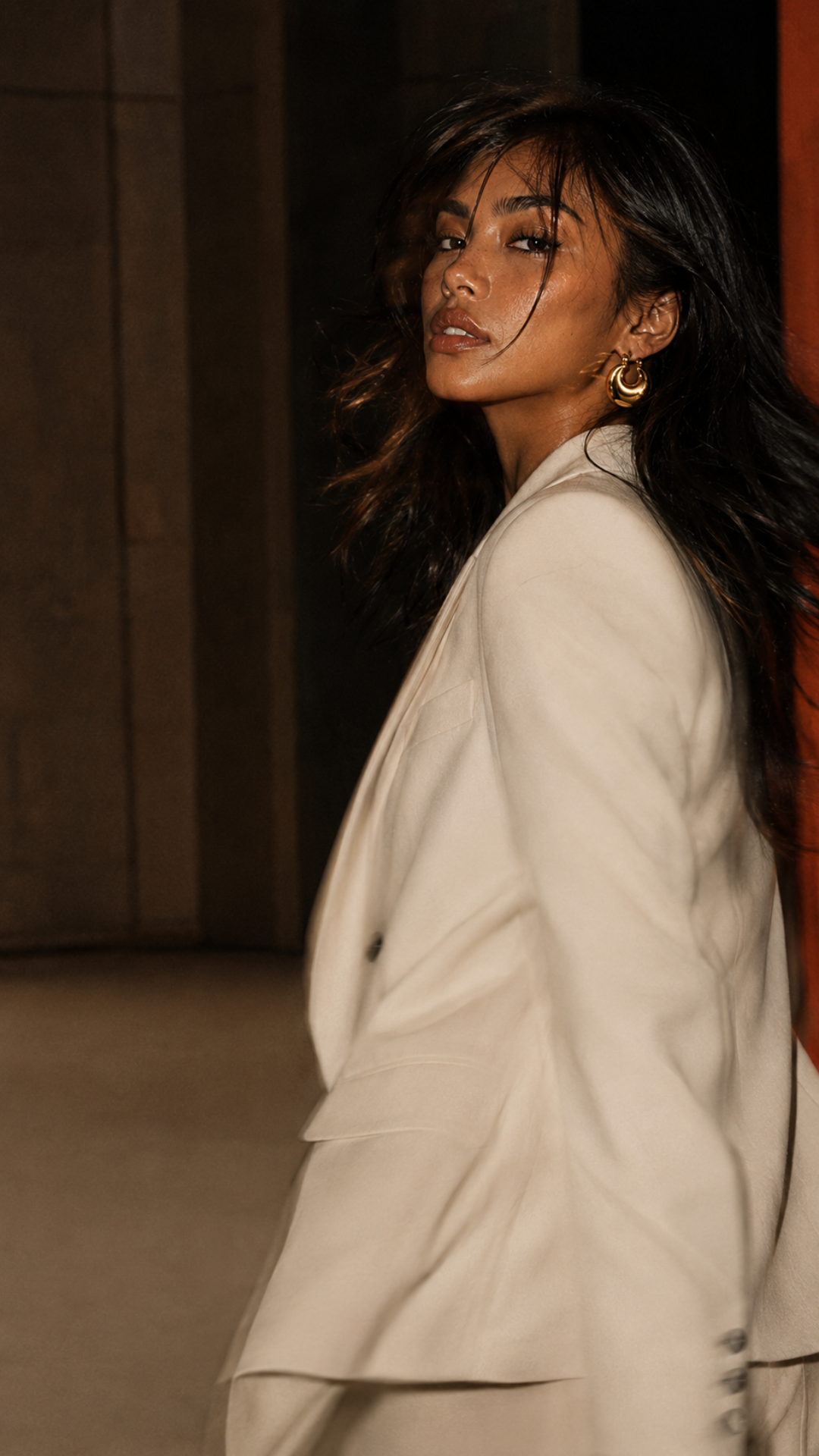 BOMBÉ model in ivory tailoring wearing sculptural gold jewelry